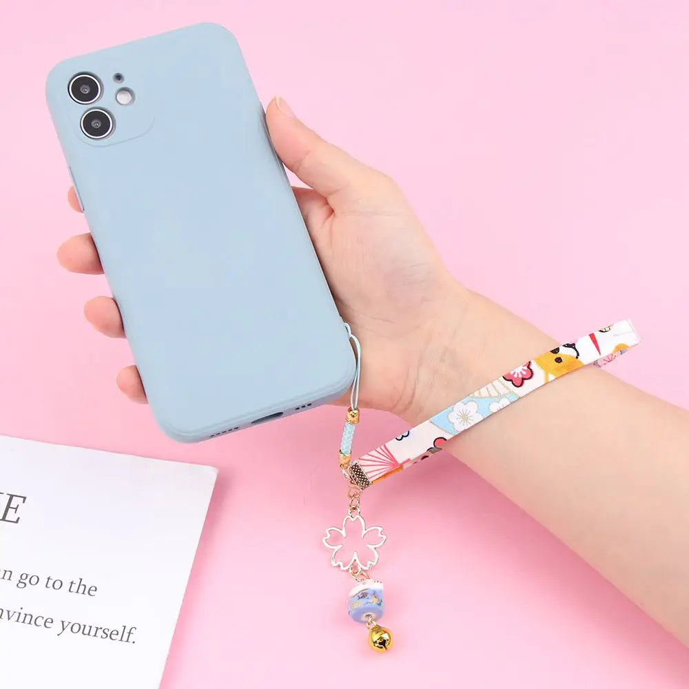 Cordón colgante para teléfono estilo japonés con diseño de flores de cerezo y gato de la suerte, en mano.
